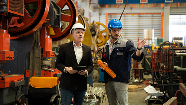 Two employees wearing hardhats in a warehouse