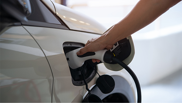 Hand plugging in EV charger to their electric car Hand plugging in EV charger to their electric car