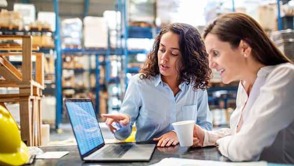Business woman working together on a laptop in a warehouse