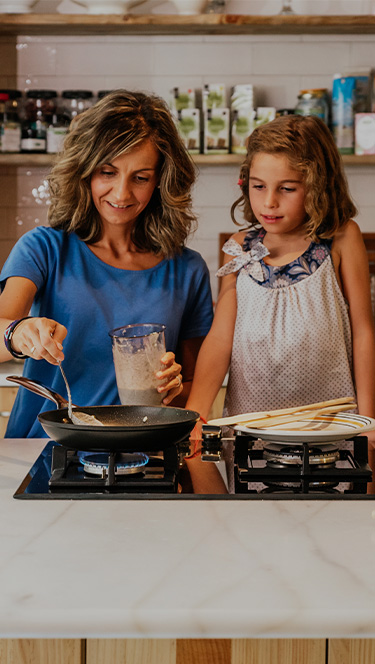 Mother and daughter cooking pancakes in their kitchen