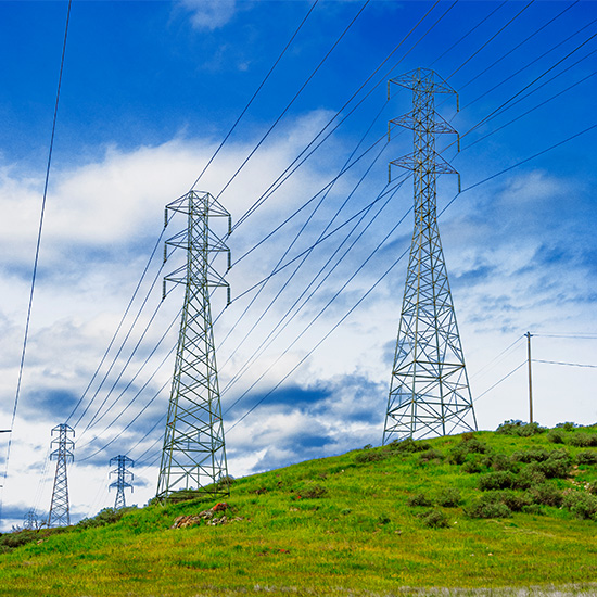 Low angle shot of power lines on a small hill