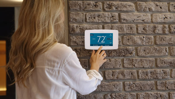 Woman adjusting her home digital thermostat Woman adjusting her home digital thermostat