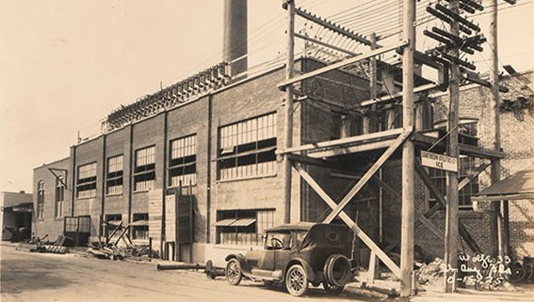 Black and white photo of old car outside and old power plant