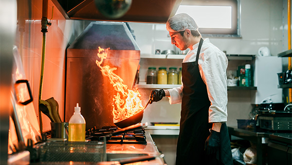 Chef cooking at a gas stove with flames