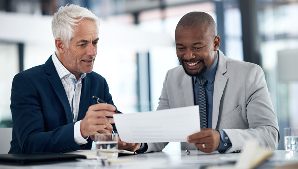 Two consultants sitting at a desk reviewing a document