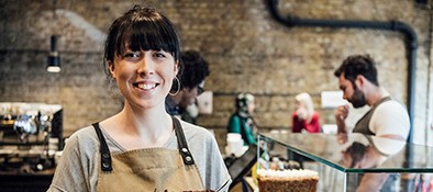 Waitress behind counter, looking at camera, small business owner working in cake shop