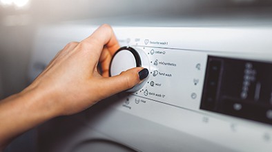 Woman’s hand settings dial on washing machine.
