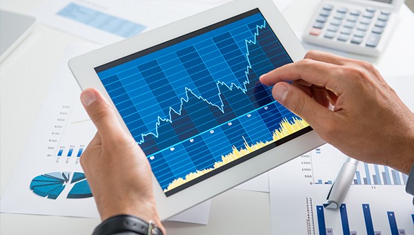close up of hand working on a tablet with energy charts displayed
