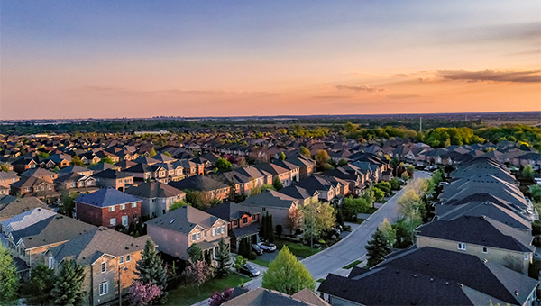 Sun rising over rooftops in a neighborhood
