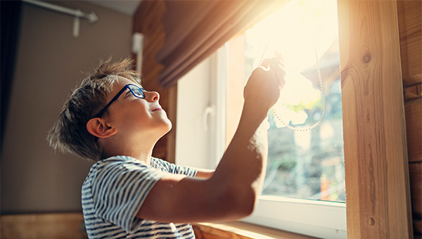 Child looking out of a sunny window in his home
