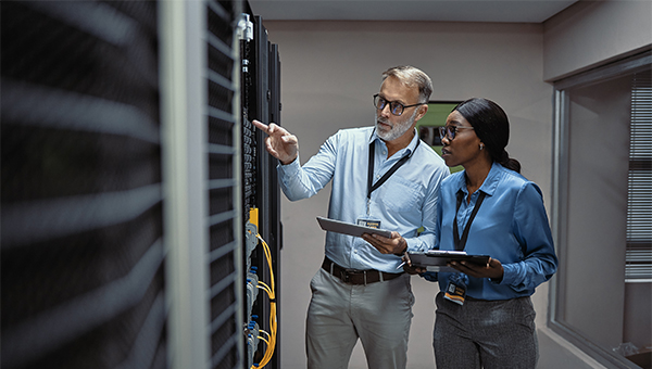 Man and woman working in a data center with tablets